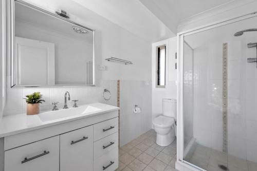 a white bathroom with a sink and a shower at Foredeck Views in Manyana