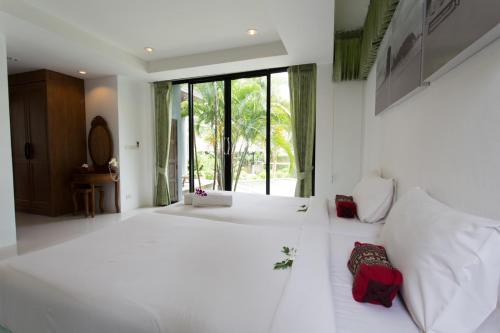 a bedroom with a large white bed with red pillows at Samui Honey Tara Villa Residence in Choeng Mon Beach