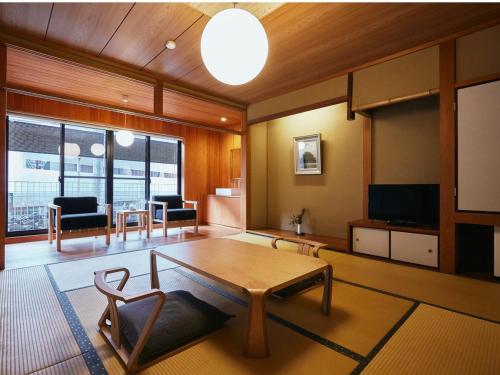 a living room with a table and a couch and a tv at TSUCHIYA Kinosaki onsen in Toyooka