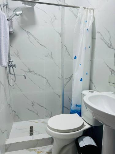 a white bathroom with a toilet and a sink at Backpackers Tashkent in Tashkent