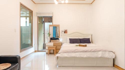 a white bedroom with a bed and a chair at Gapyeong Namian Pool Villa in Gapyeong