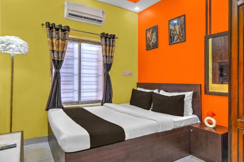 a bedroom with a bed with an orange wall at Hotel O Bangur Kolkata Formerly The Avenue Inn in Nager Bazaar