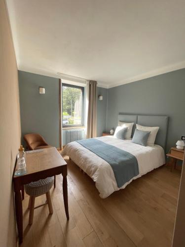 a bedroom with a bed and a table and a window at Fleurs de lin in Saint-Brieuc-des-Iffs