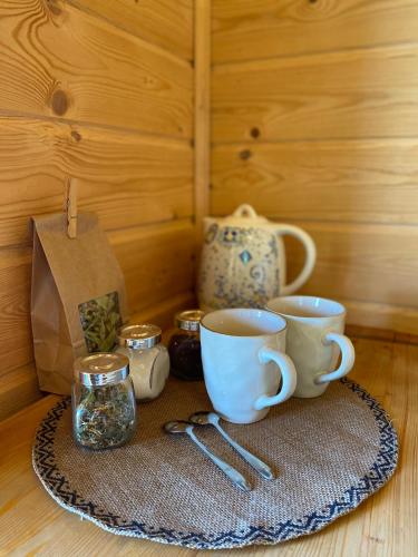 a table with two coffee cups and a tea pot at Cozy chalet for nature lovers in Ķevele