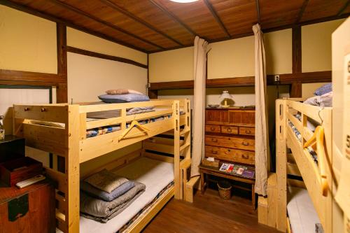 two bunk beds in a room with wooden ceilings at はやちねの宿ラビット in Hanamaki