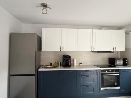 a kitchen with blue cabinets and a refrigerator at Aero Comfort Apartment in Cluj-Napoca