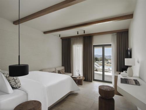 a bedroom with a large white bed and a living room at Parian Chronicle Hotel Paros, Destination by Hyatt in Kampos Paros