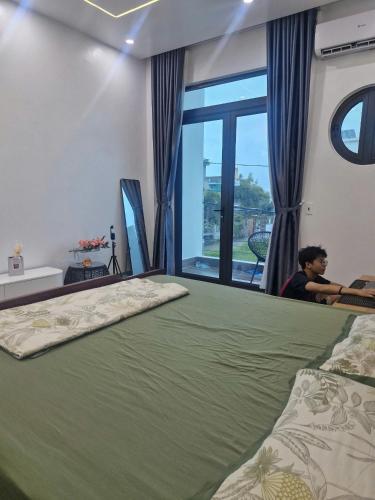 a man sitting in a room with a large bed at Home Phong Vân in Hâu Thon