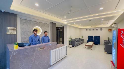 two men standing behind a counter in a lobby at Hotel Sugandh Retreat Near Bus Stand Jaipur in Jaipur