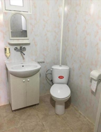 a bathroom with a white toilet and a sink at Стаи за гости Дворъ in Varna City