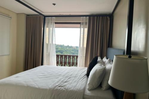 a bedroom with a large bed with a window at Crosswinds Swiss Deluxe Suite in Tagaytay