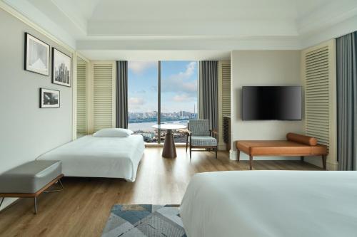 a hotel room with two beds and a flat screen tv at Sheraton Shanghai Pudong Riverside in Shanghai