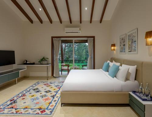a bedroom with a large bed and a television at Lamrin Morjim Goa in Morjim