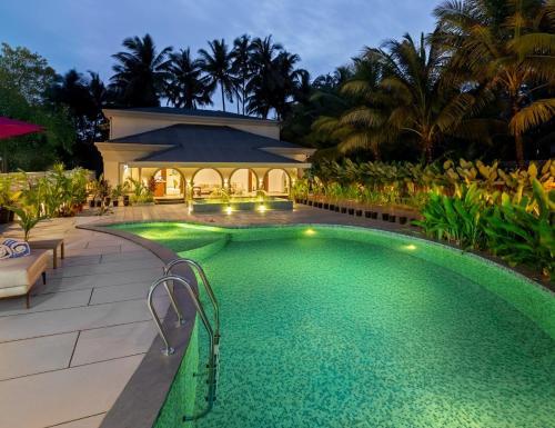 a swimming pool in front of a house at Lamrin Morjim Goa in Morjim