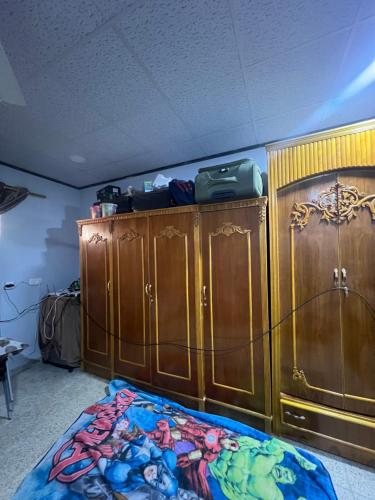 a bedroom with wooden cabinets and a bed with a blanket at Traveler rest in Arbājīyah