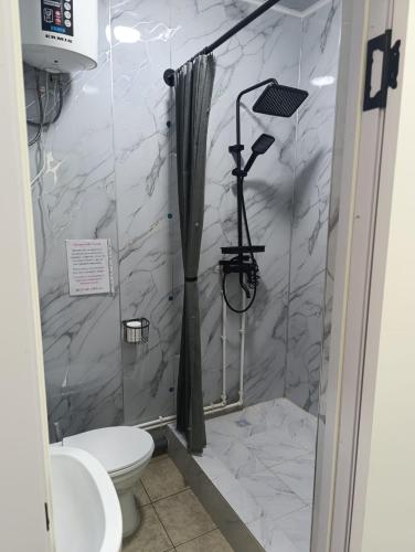 a bathroom with a shower with a toilet and a sink at Саратан отель in Osh