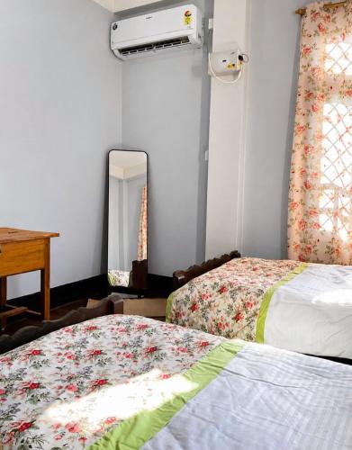 a bedroom with two beds and a mirror and a piano at sicsac inn in Jorhat