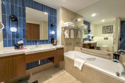 a bathroom with a tub and a sink and a mirror at Ramada by Wyndham Downtown Dubai in Dubai