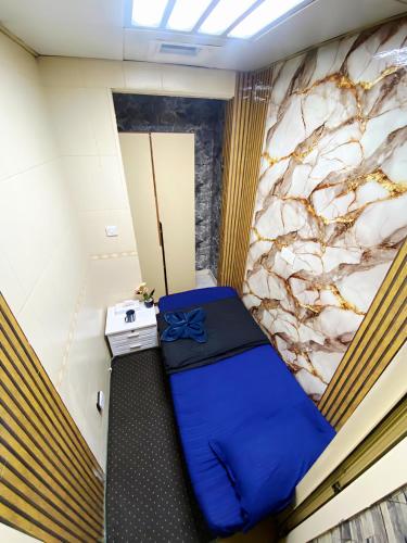 a small room with a blue bed in a room at Cozy Beyond Simple in Abu Dhabi