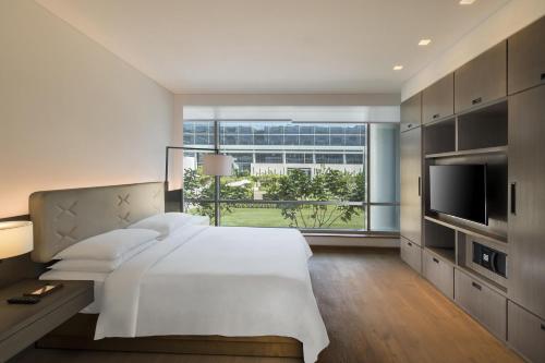 a bedroom with a large bed and a large window at Andaz Delhi, by Hyatt in New Delhi