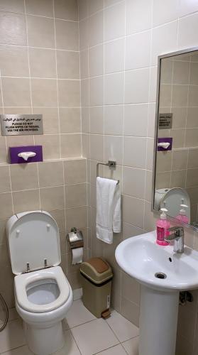 a bathroom with a toilet and a sink at Cozy Beyond Simple in Abu Dhabi