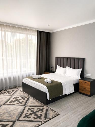 a bedroom with a large bed and a large window at Dosman Hotel Bishkek in Bishkek