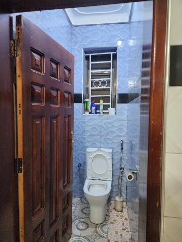 a bathroom with a toilet in a blue tiled room at Rippon Nest in Jinja