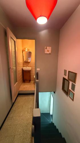 a hallway with a bathroom with a sink and a red light at Verde Salvia House in Corniglio