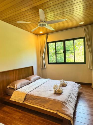 a bedroom with a bed with a ceiling fan at Naruemon in Ban Madua Wan