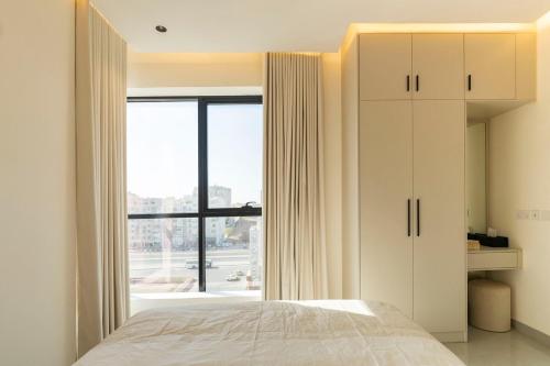 a bedroom with a bed and a large window at Beige Apartment by Bait Zain - Bousher in Muscat