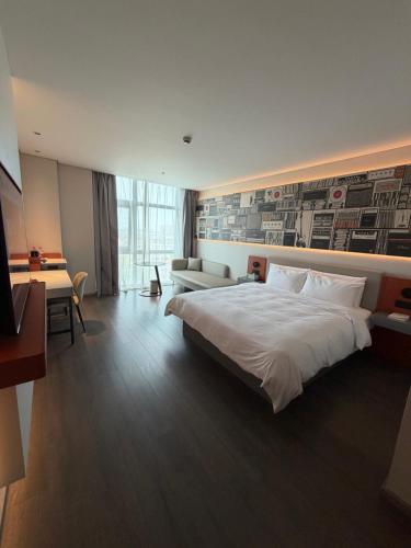a bedroom with a large white bed and a couch at Ibis Haiyan Economic Development Zone in Haiyan