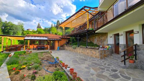 a house with a patio and a garden with flowers at Guest House Panorama in Gela