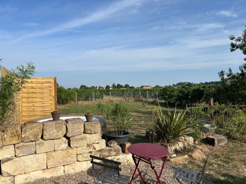 a patio with a stone wall and a table at L’Orée des Vignes in Saint-Sulpice-de-Faleyrens