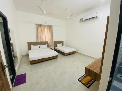 a white room with two beds and a window at Takery Resort in Chittaurgarh