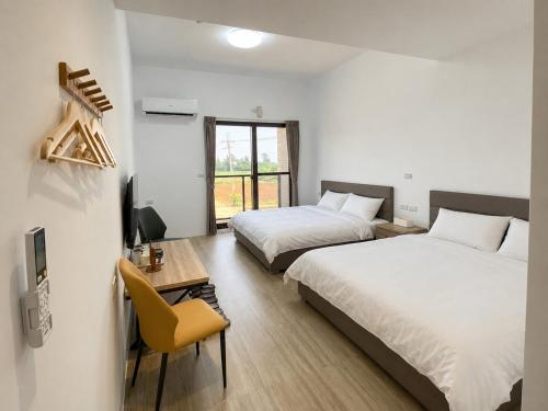 a bedroom with two beds and a desk with a chair at Hai Jing Man Lu B&B in An-hsia