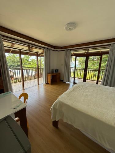 a bedroom with a bed and a balcony with windows at Takbo Beach Resort in General Luna