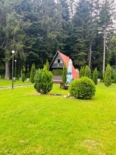 a cabin in a park with a green field and trees at Chalet Musala in Borovets