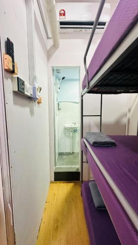 a purple bunk bed in a room with a bathroom at Bidara Guest House in Kampong Sungai Baru Tengah