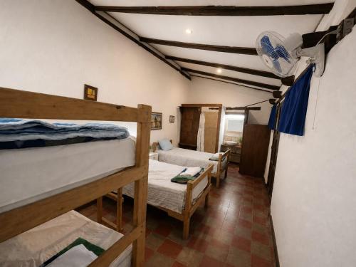 a room with three bunk beds and a bathroom at Hostal Casona de los Vega in Sonsonate