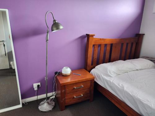 a bedroom with a bed and a lamp on a night stand at Sunset in Pakenham in Pakenham