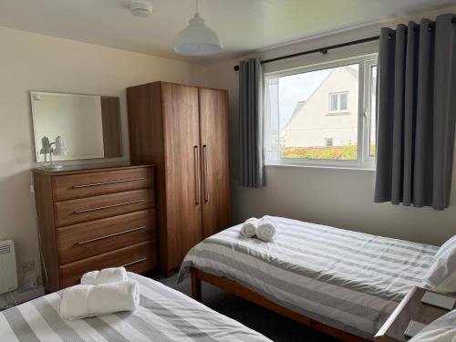 a bedroom with two beds and a dresser and a window at Copthorne - Tintagel in Tintagel