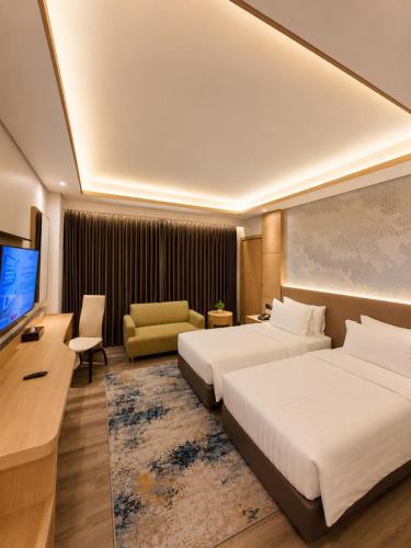 a hotel room with two beds and a flat screen tv at Orchardz Hotel Industri Jakarta Kemayoran in Jakarta