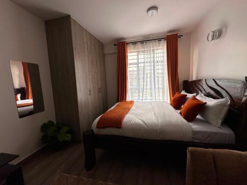 a bedroom with a bed with orange and white pillows at Homes by Sil Bn in Muchatha