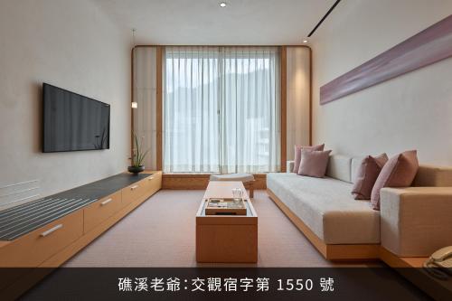 a living room with a couch and a flat screen tv at Hotel Royal Chiao Hsi in Jiaoxi