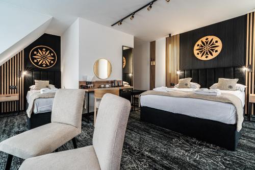 a hotel room with two beds and a desk and chairs at Malinowy Potok in Białka Tatrzańska
