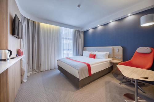 a hotel room with a bed and a red chair at Holiday Inn Express - Yerevan by IHG in Yerevan