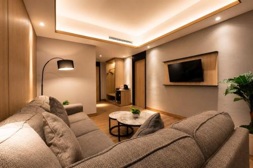 a living room with a couch and a tv at Orchardz Hotel Industri Jakarta Kemayoran in Jakarta