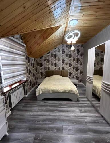 a bedroom with a bed and a wooden ceiling at Yusubovs in Hacıkǝnd