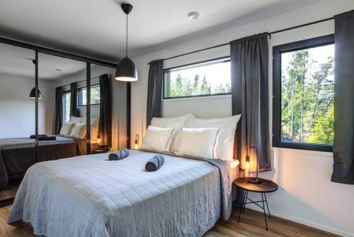 a bedroom with a large bed and two windows at Villa Syreeni - Seafront/Jacuzzi in Kilpilahti