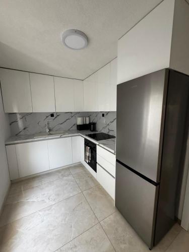 a kitchen with white cabinets and a stainless steel refrigerator at Villa M in Neum